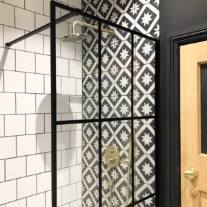 The shower area with crittal style shower screen, patterned tiles and gold shower. 