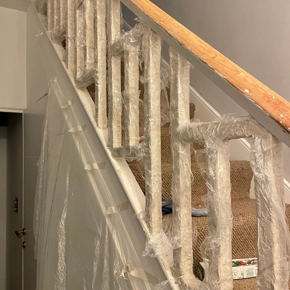 The spindles of the staircase with the Kling Strip applied and covered in cling film. 